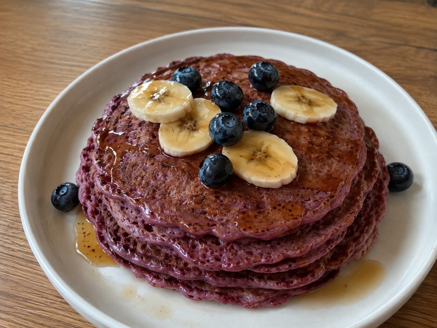 Stapel paarse pannenkoeken met banaan en blauwe bessen